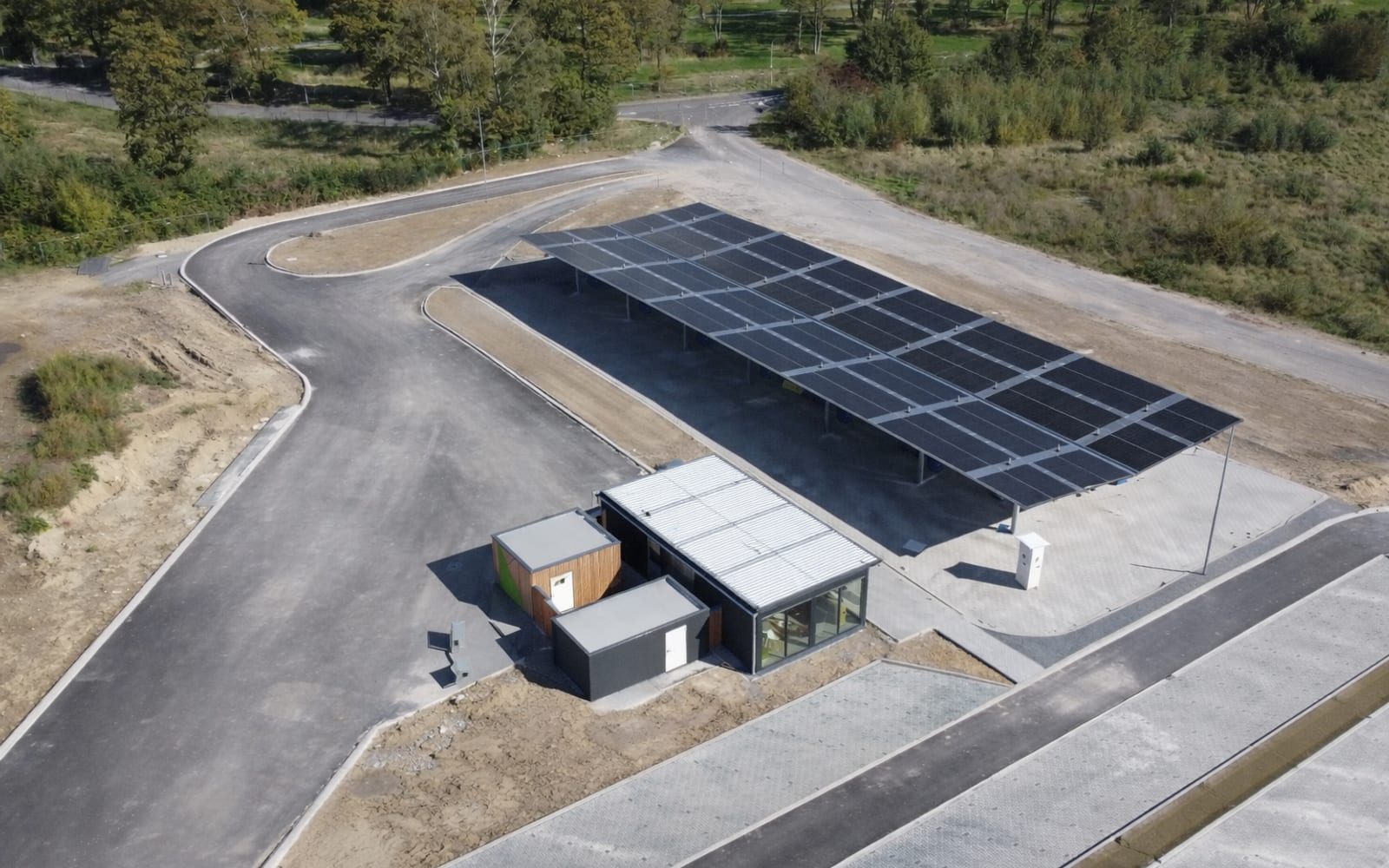Luftaufnahme eines Solar-Ladeparks mit überdachten Stellplätzen und angeschlossenem Betriebsgebäude