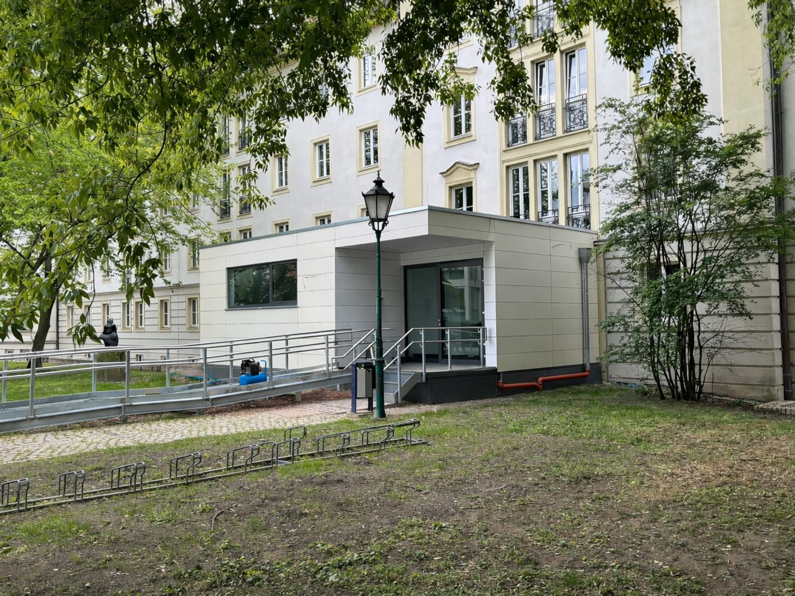 Barrierefreier Zugang mit Rampe an einem denkmalgeschützten Gebäude, ergänzt durch einen hellen Anbau