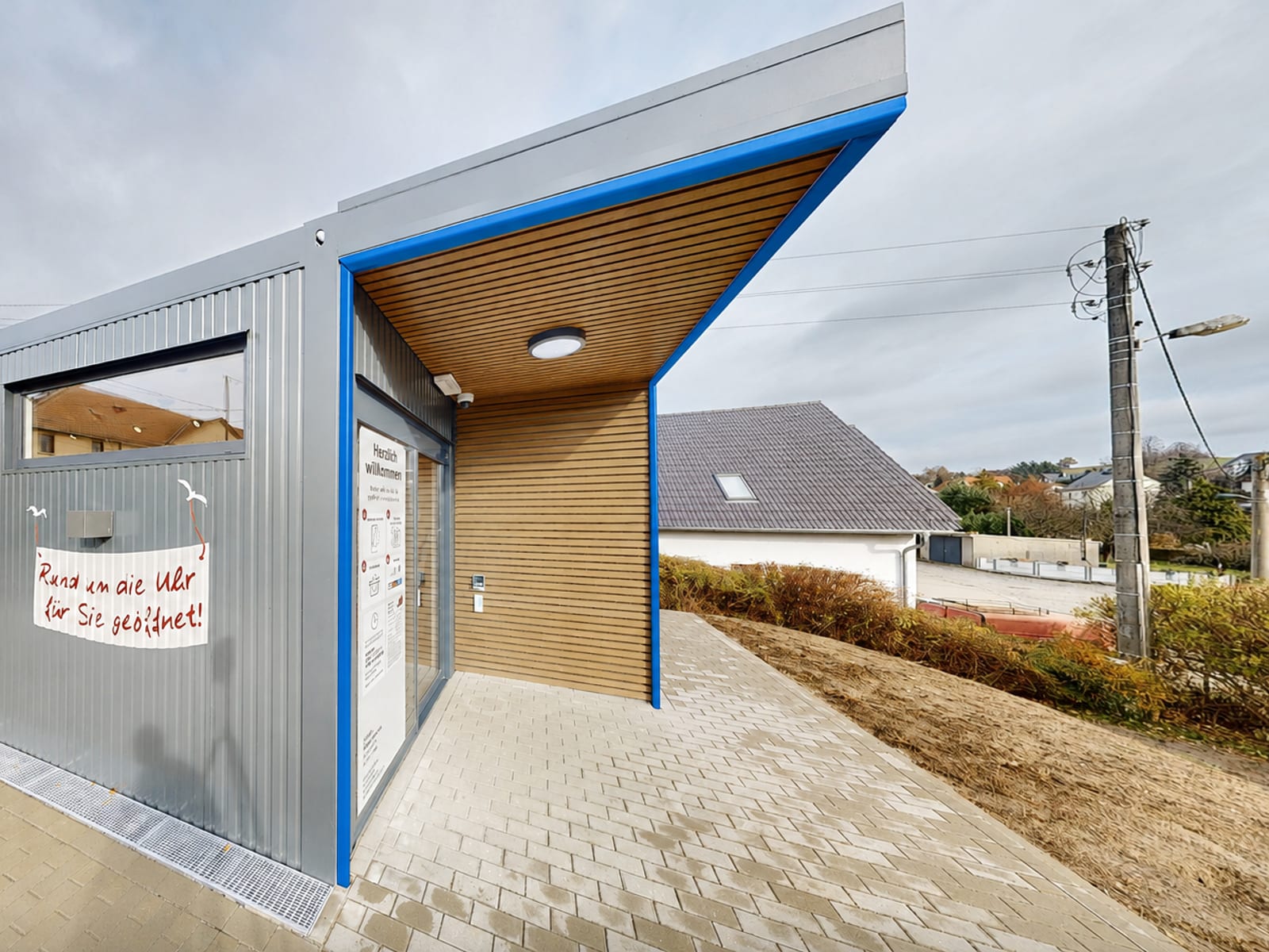 Autonomer Smart Store mit holzverkleidetem Eingangsbereich und blau abgesetzter Fassade